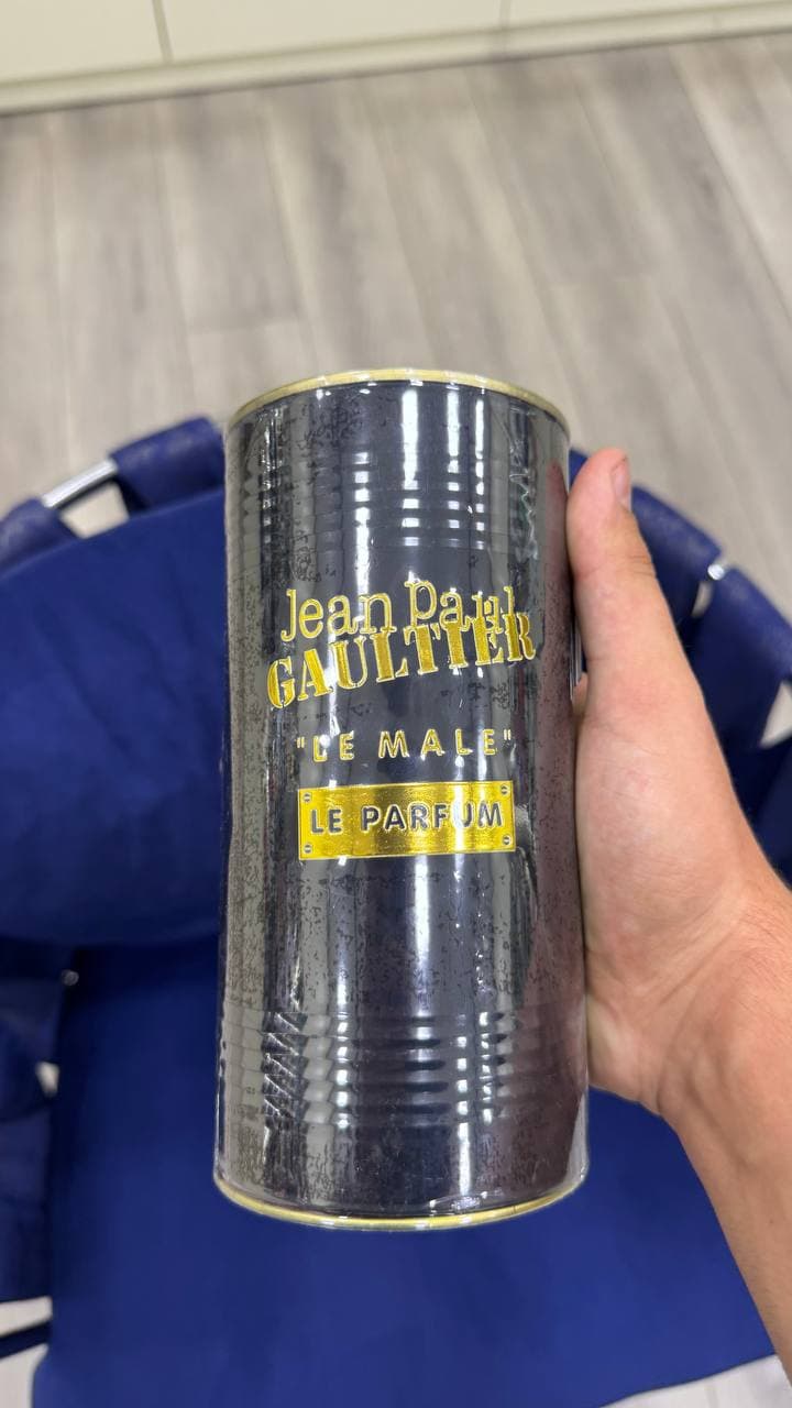 Металлическая цилиндрическая упаковка духов Jean Paul Gaultier "Le Male" с золотыми надписями.
