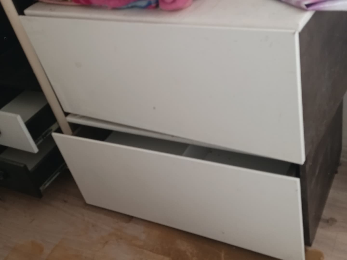 Белая тумбочка с двумя ящиками, один из которых открыт.