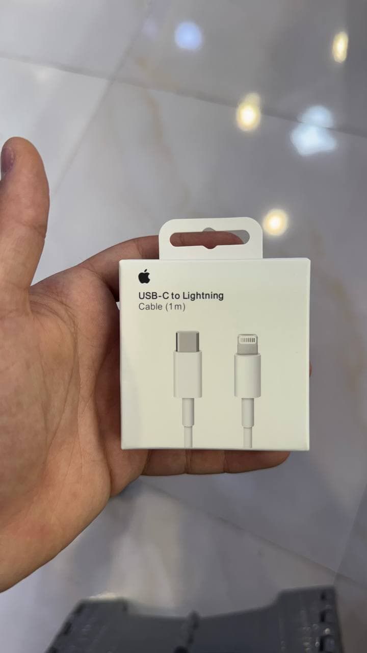 Коробка с кабелем USB-C to Lightning в руке на светлом фоне.