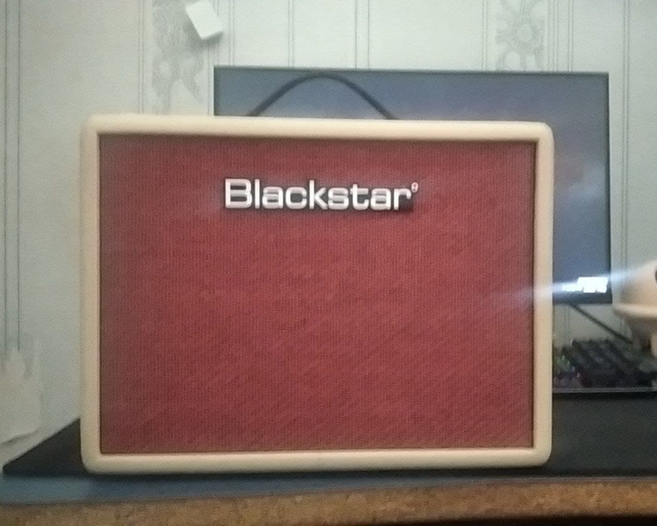 Гитарный комбоусилитель Blackstar с красной решёткой и белой рамкой.