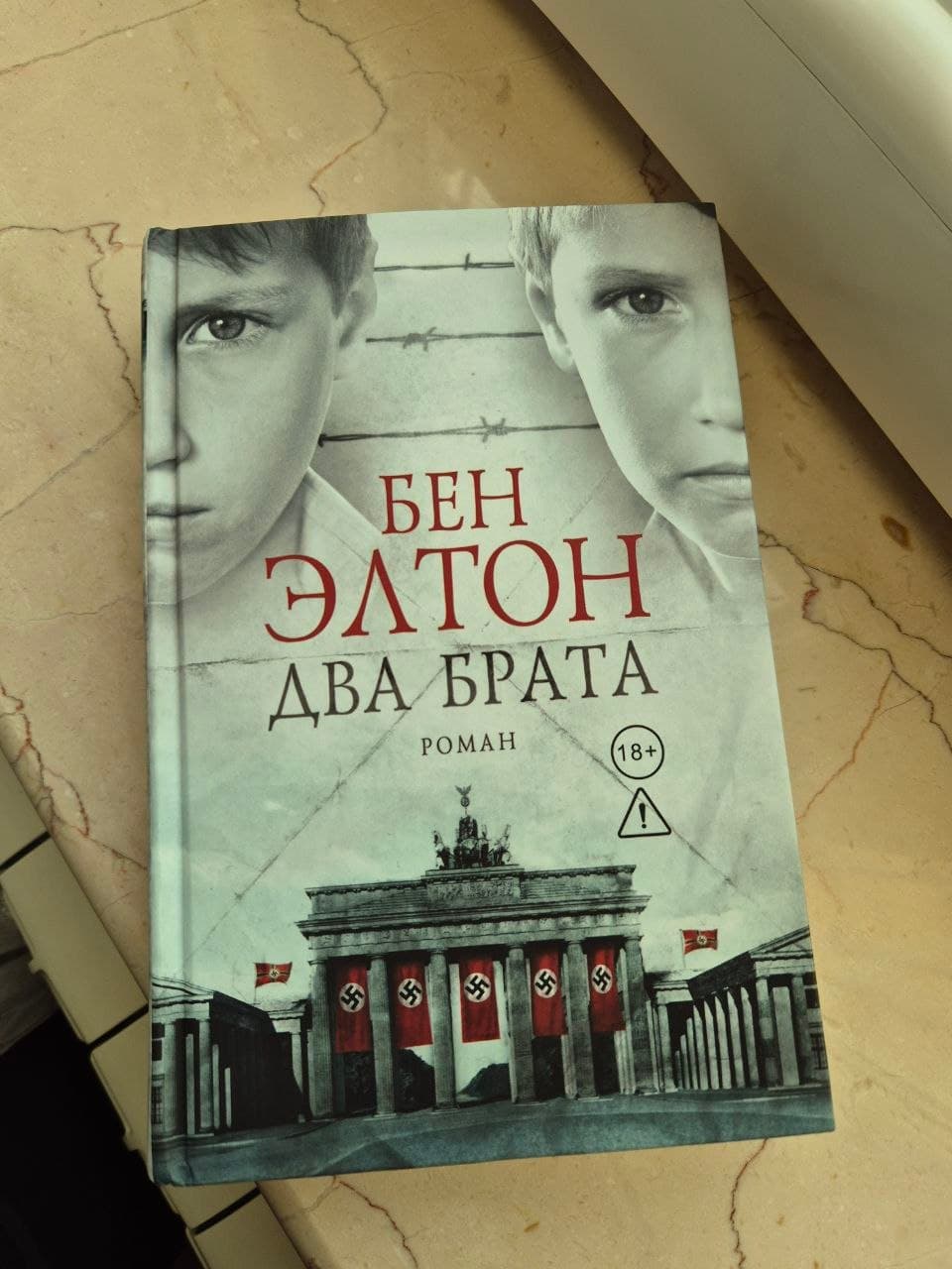 Книга "Два брата" Бена Элтона в твердом переплете с изображением двух мальчиков и здания с нацистскими флагами на обложке.
