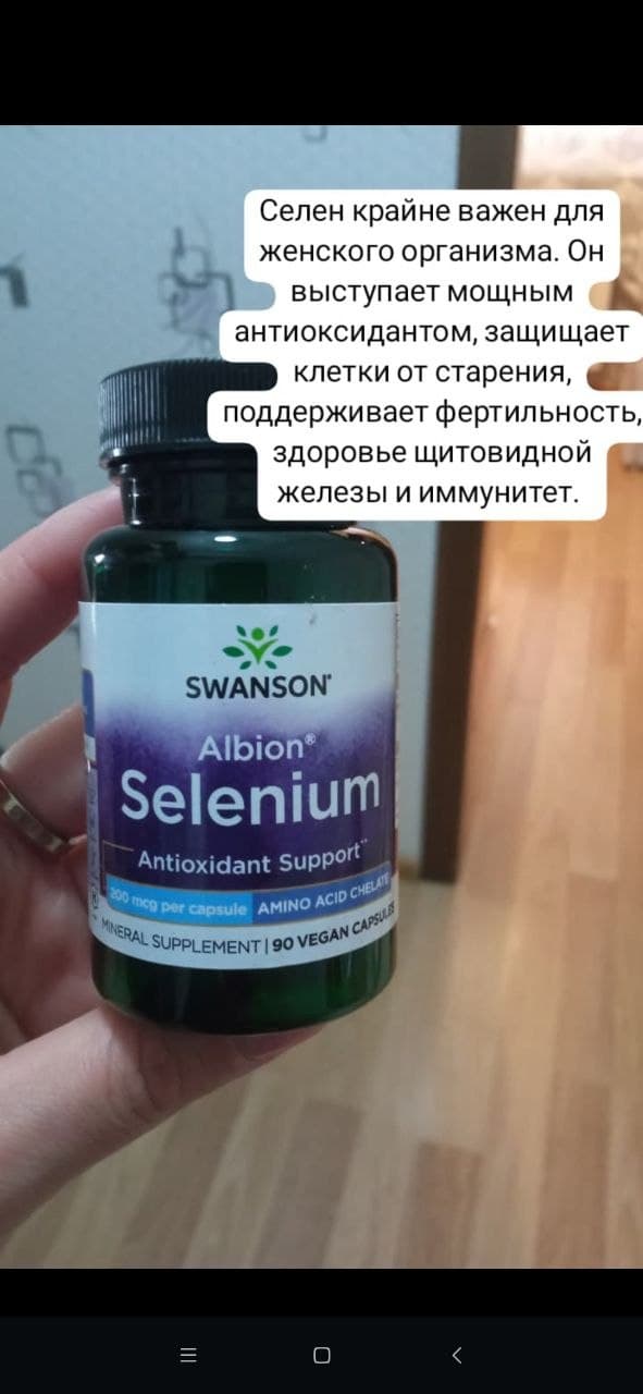 Бутылка с добавкой Swanson Albion Selenium в руке на фоне пола.