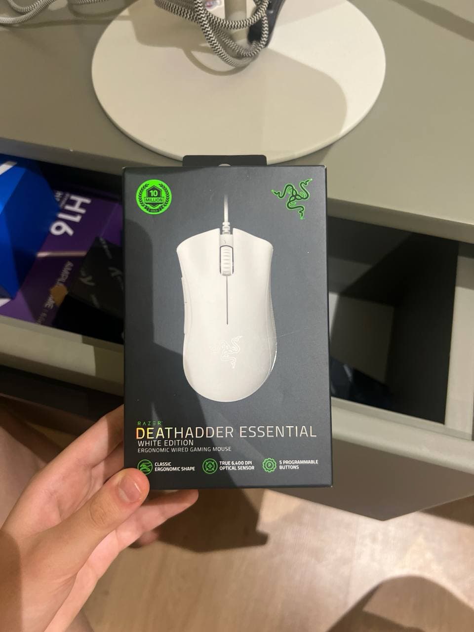 Коробка с белой проводной игровой мышью Razer DeathAdder Essential White Edition в руке.