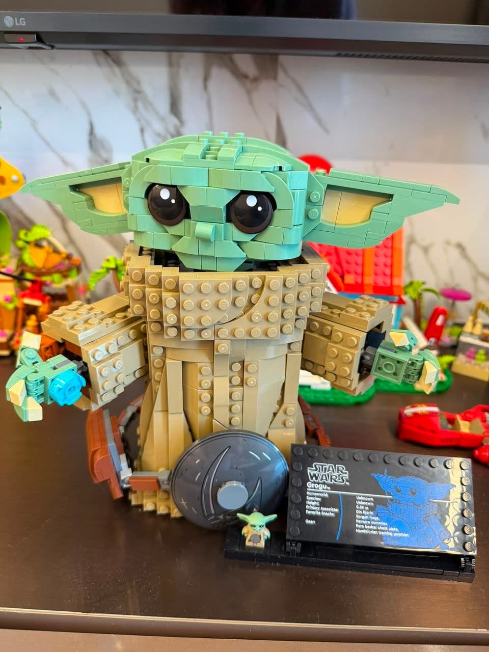 Собранный конструктор LEGO персонажа Грогу из "Звёздных войн" с табличкой и мини-фигуркой.