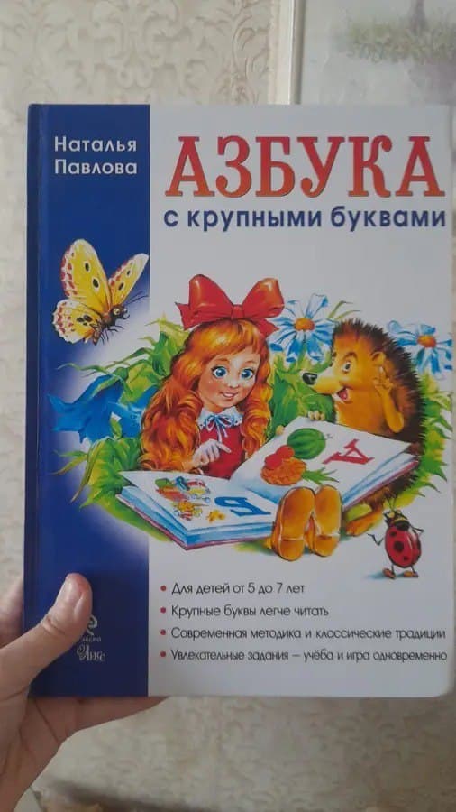 Детская книга "Азбука с крупными буквами" с иллюстрацией девочки и ёжика на обложке.