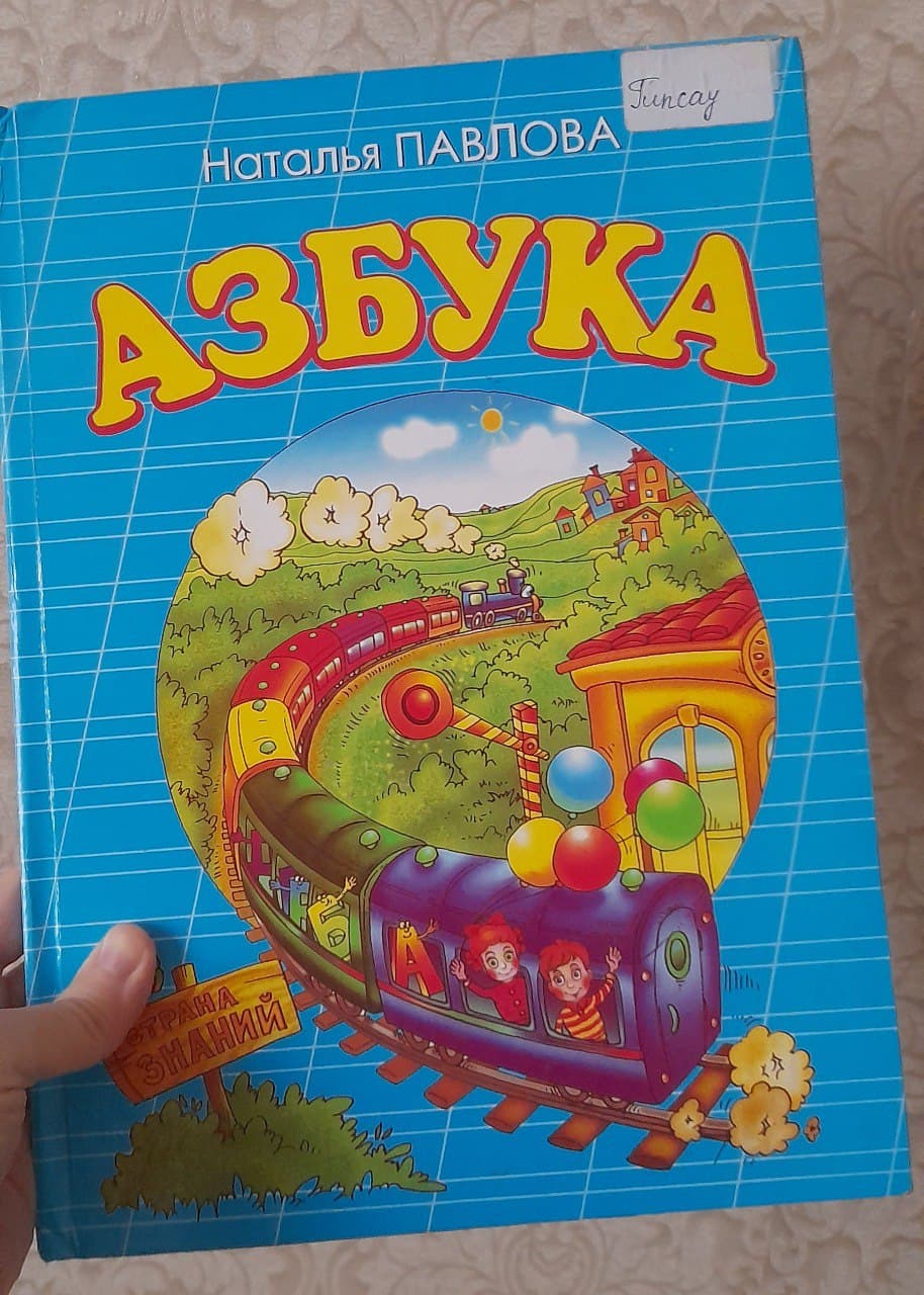 Обложка детской книги "Азбука" с изображением поезда и детей.