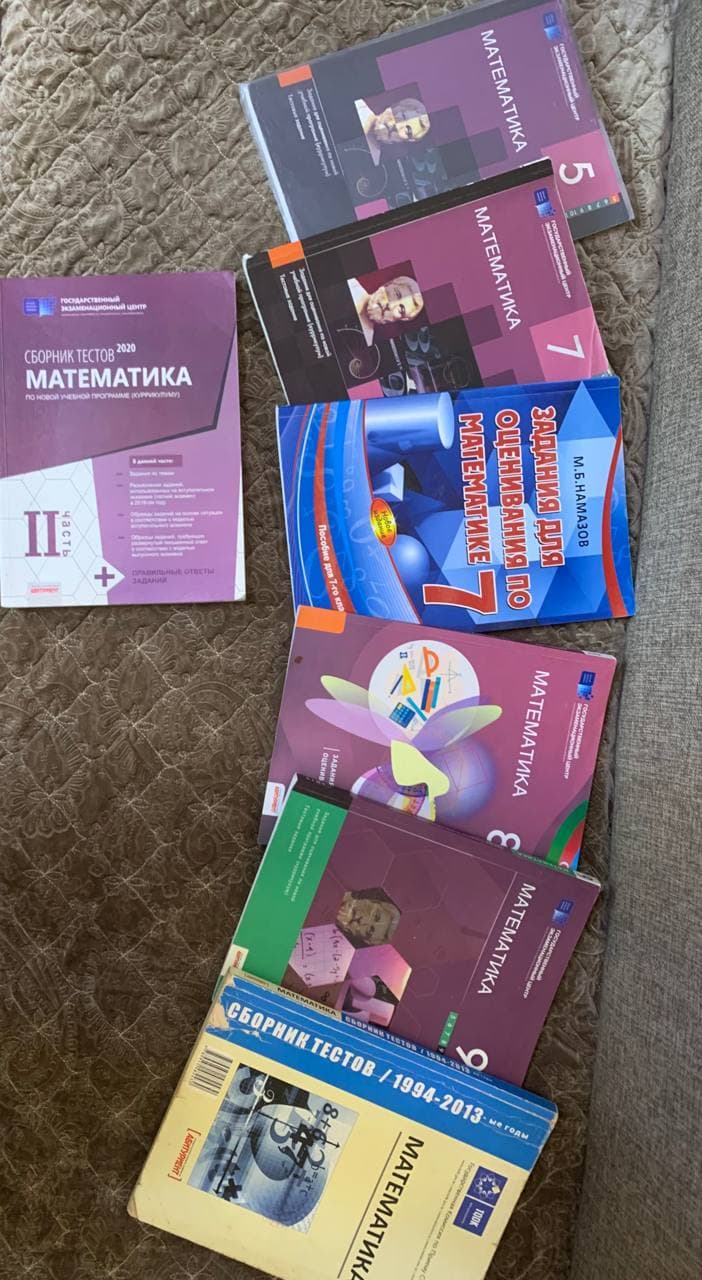 Несколько книг и сборников тестов по математике, разложенных на покрывале.