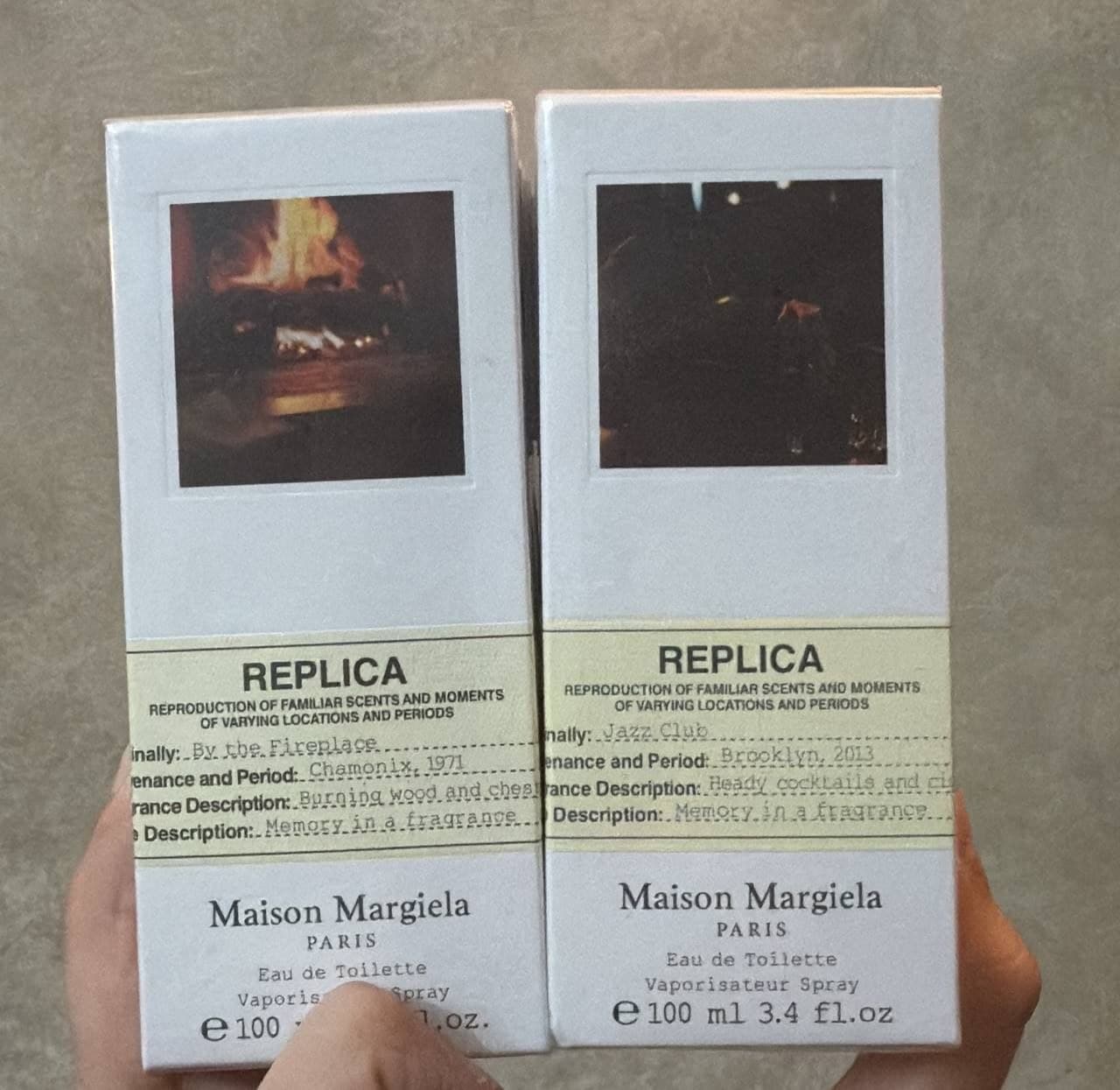 Две коробки парфюмерной воды Maison Margiela Replica с разными ароматами и изображениями.