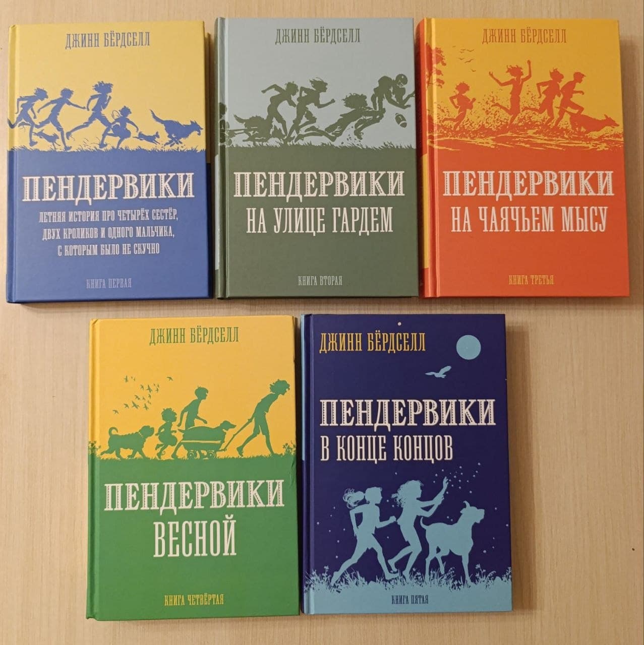 Пять книг серии "Пендервики" с разноцветными обложками, разложенные на столе.