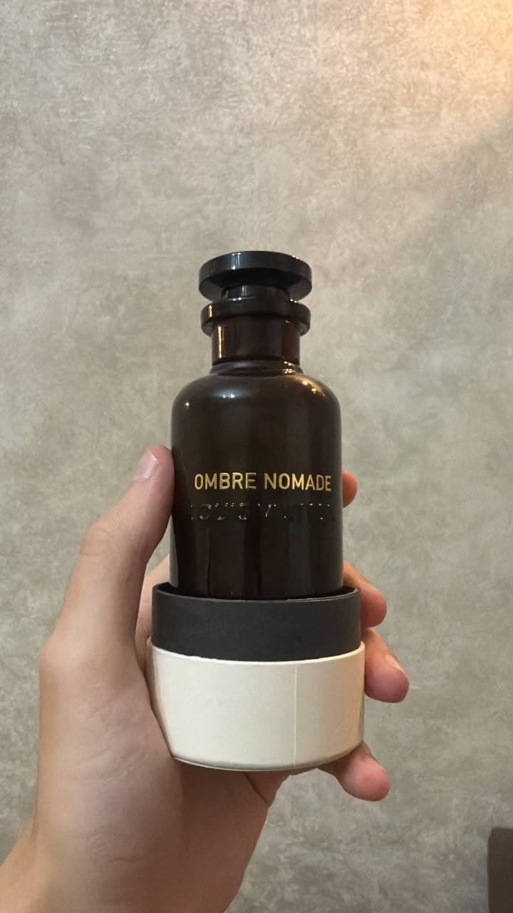 Флакон духов OMBRE NOMADE в руке на светлом фоне.