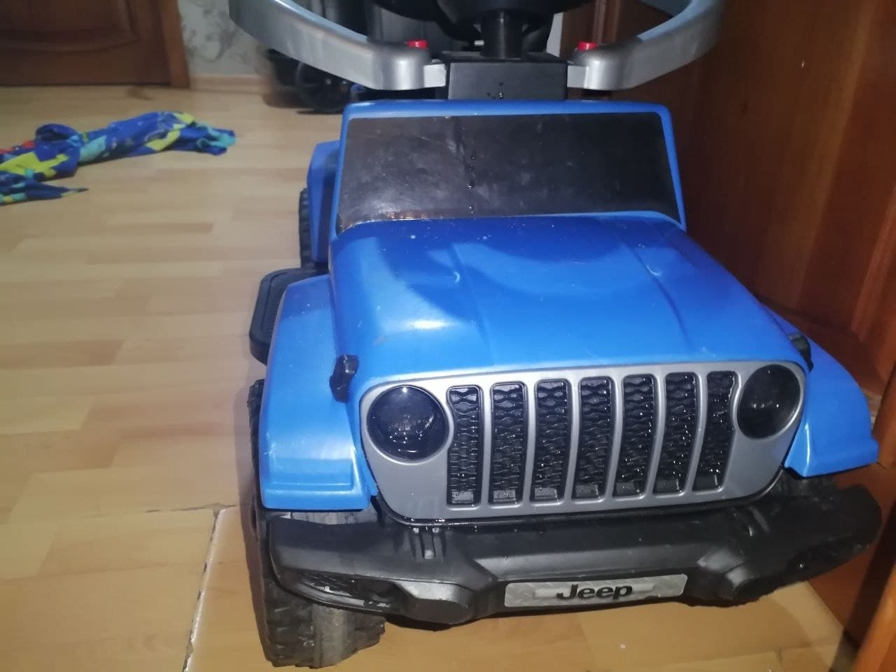 Детская синяя игрушечная машина с надписью Jeep на переднем бампере.
