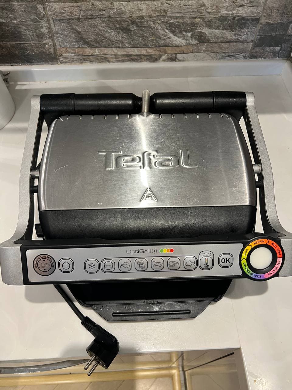 Электрогриль Tefal Optigrill с закрытой металлической крышкой и панелью управления.