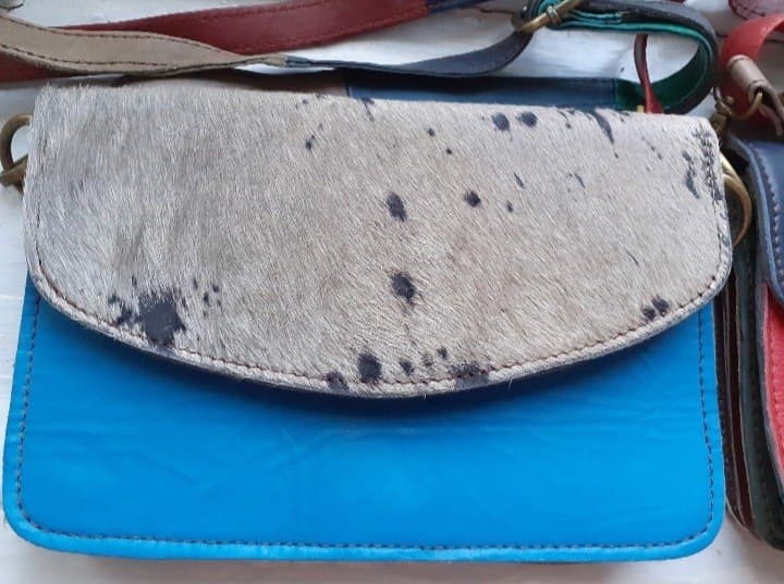 Сумка с синей кожаной основой и пятнистым меховым клапаном.