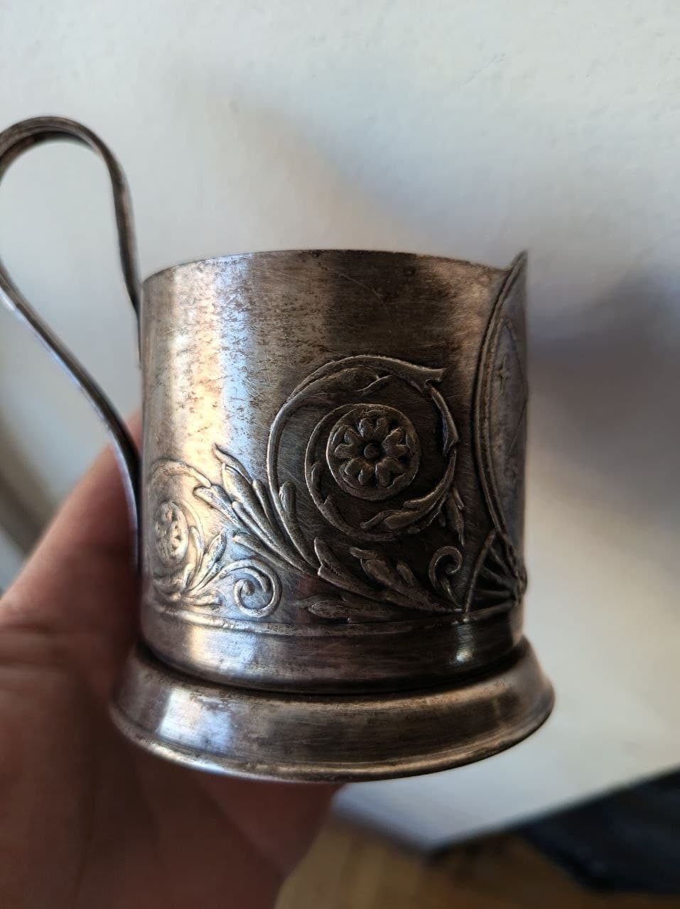 Подстаканник из мельхиора с цветочным орнаментом и ручкой.