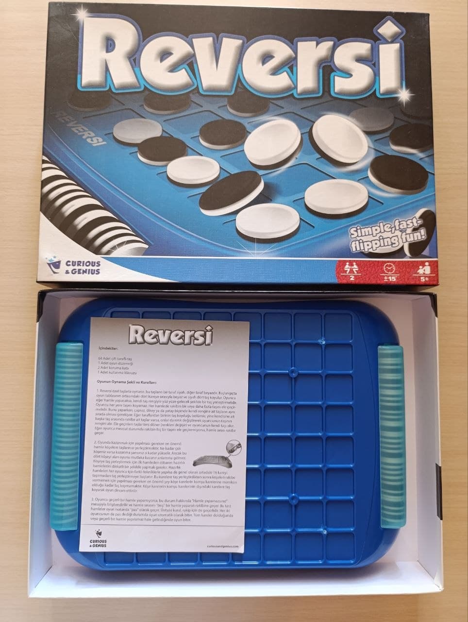 Настольная игра Reversi в открытой коробке с синей доской и инструкцией.