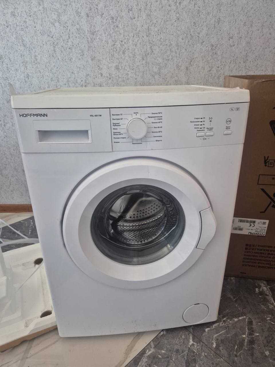 Фронтальная белая стиральная машина Hoffmann VSL-6011W с открытым люком и панелью управления.