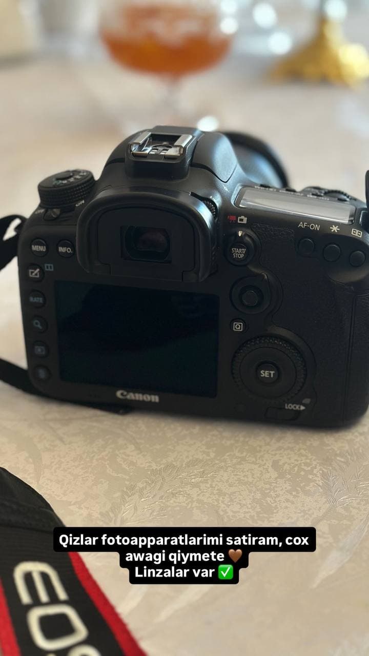 Фотоаппарат Canon с экраном и кнопками управления на светлой поверхности.