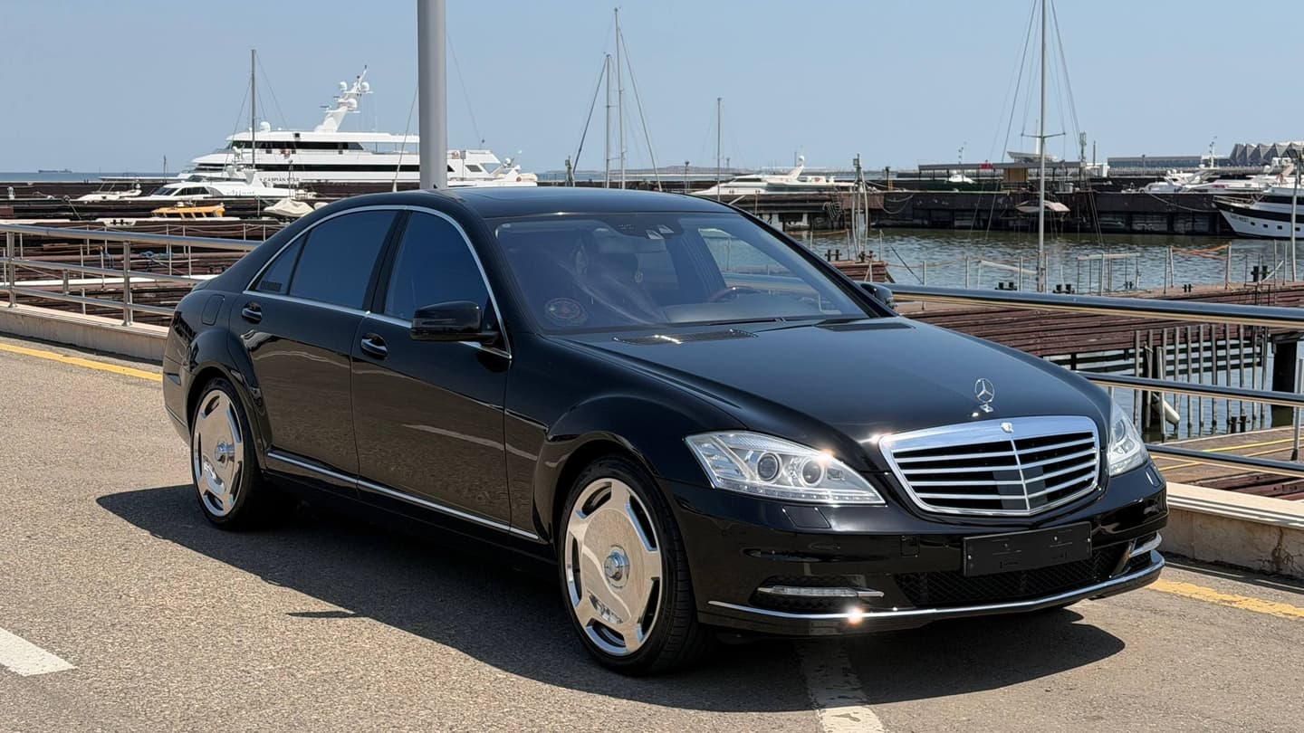 Чёрный Mercedes-Benz W221 Long 2013 года на фоне причала с яхтами.