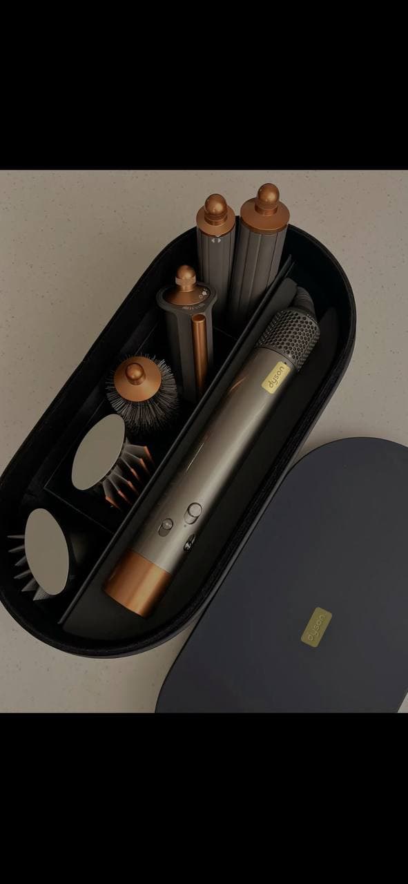Набор для укладки волос Dyson в чёрном кейсе с несколькими насадками.