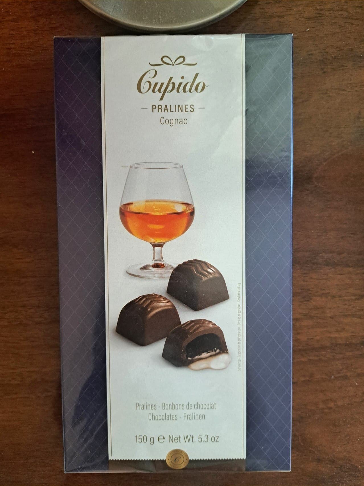 Коробка конфет Cupido Pralines с изображением шоколадных конфет и бокала коньяка.
