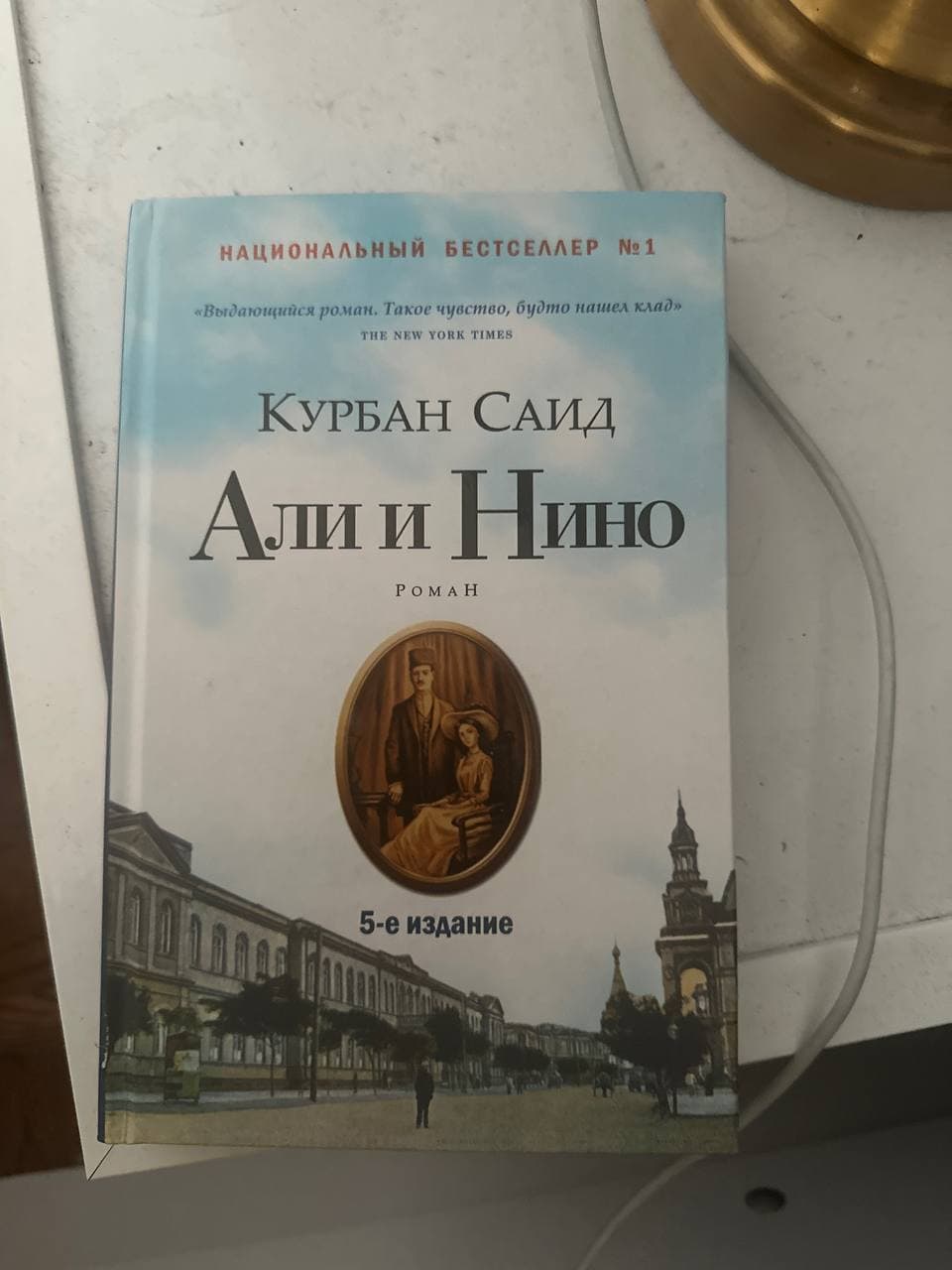 Книга "Али и Нино" Курбан Саид, 5-е издание, на голубой обложке с изображением улицы и портрета.